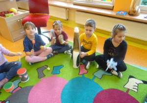 Czwórka dzieci siedzi z instrumentami muzycznymi wykonanymi z materiałów pochodzących z recyklingu.